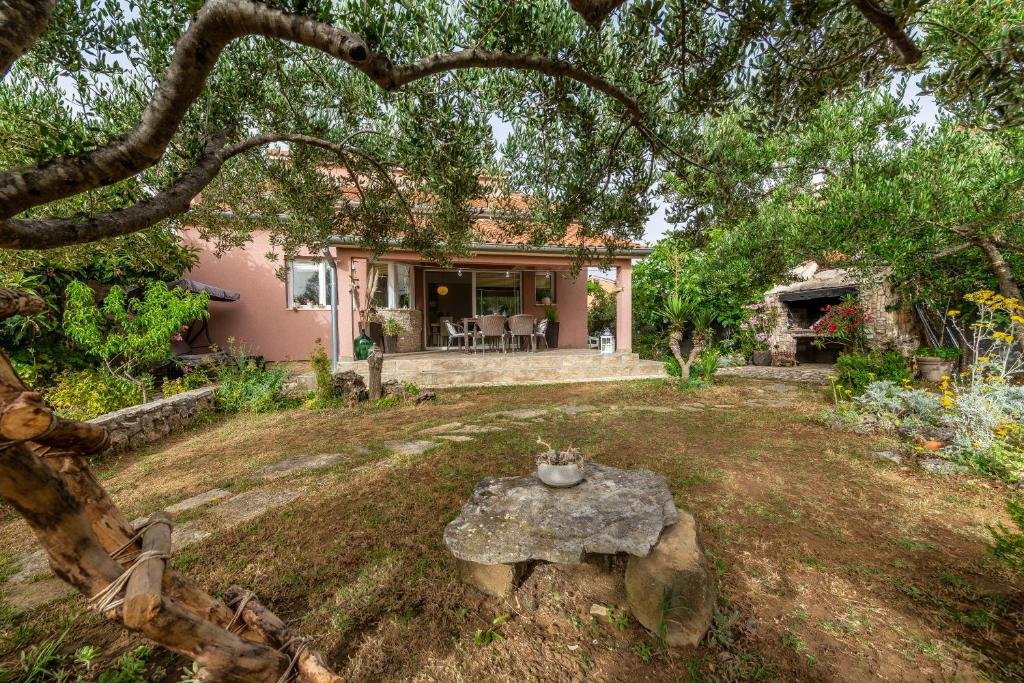 Private garden under old olive trees with a stone table and the terrace behind