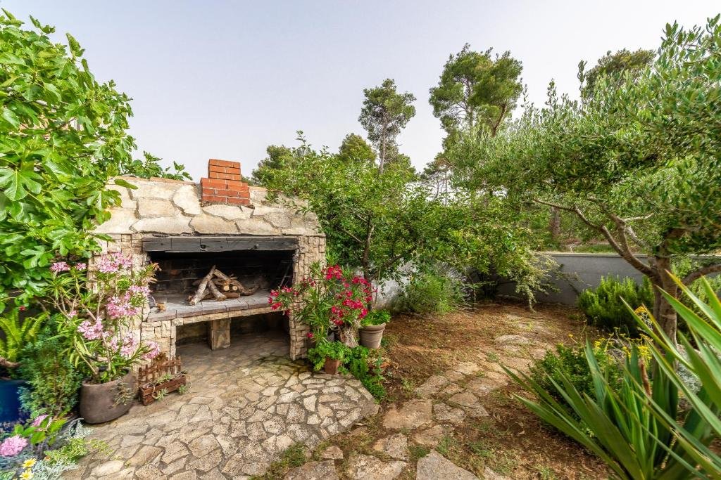 Traditional stone barbecue surrounded by flowers and olive trees